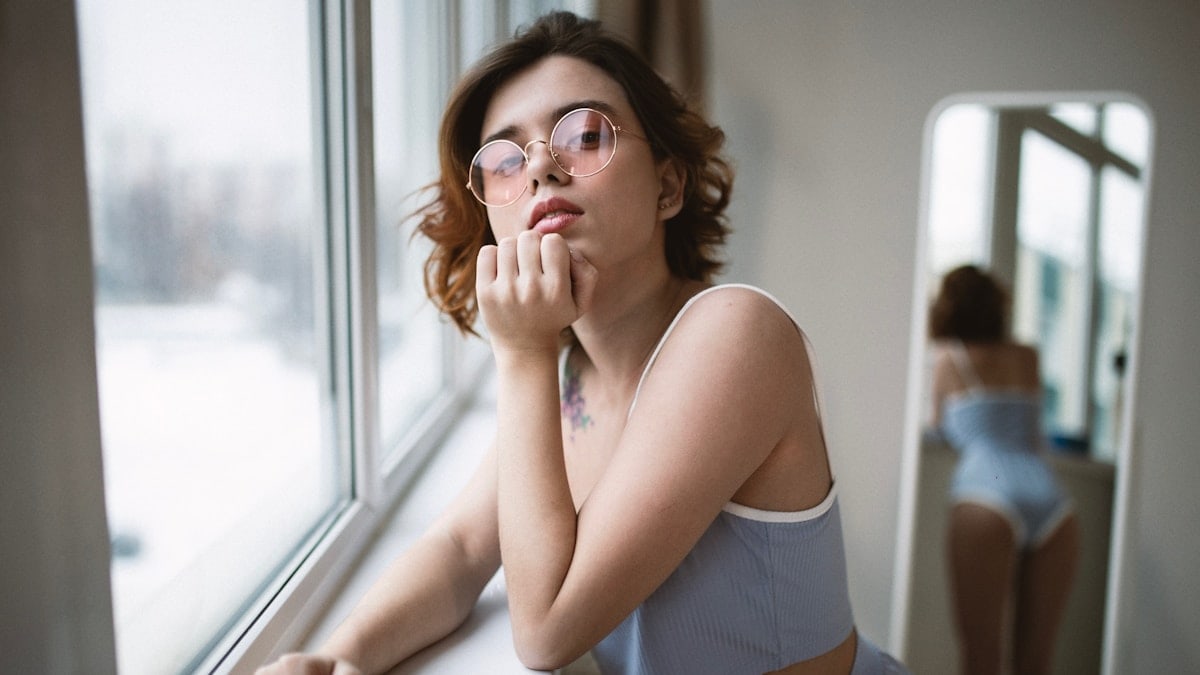 a woman with glasses looking out of a window